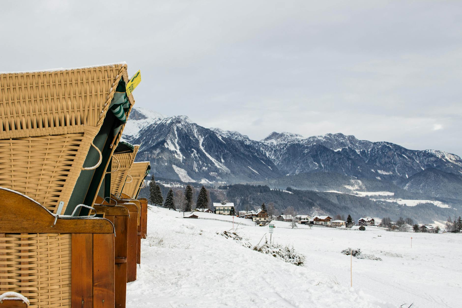 Zimowy taras z wiklinowymi krzesłami z widokiem na alpejską wioskę