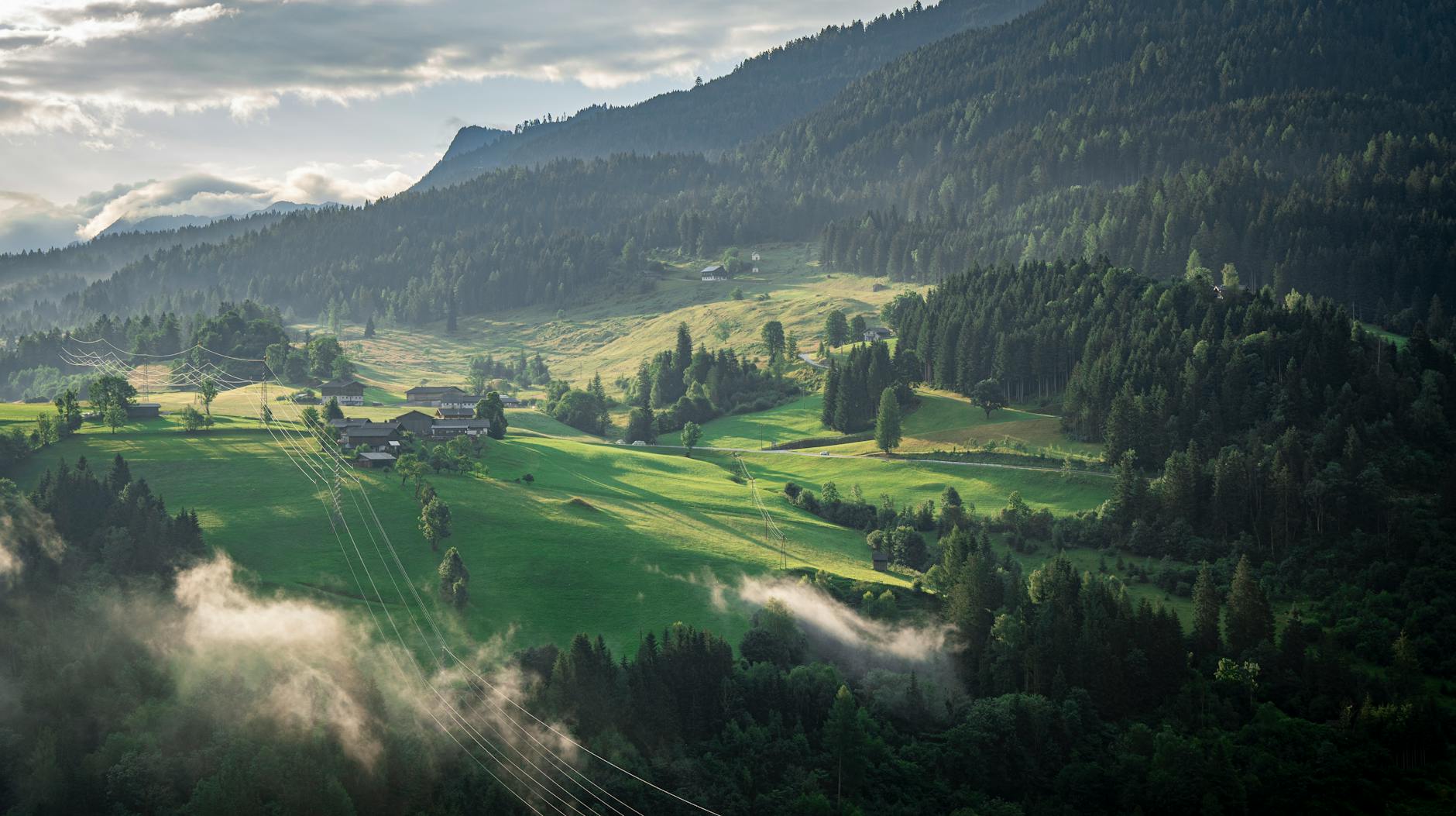 Zielone alpejskie zbocza Vorarlbergu we mgle i lesie