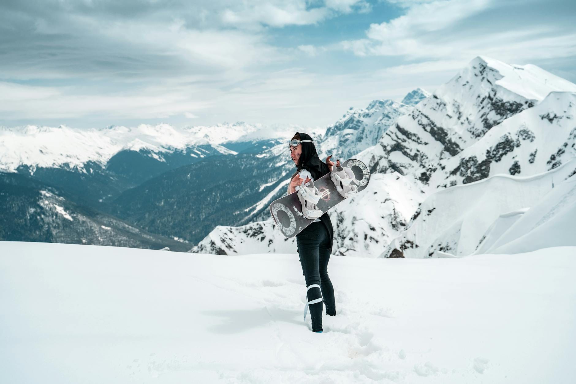 Snowboardzistka z deską na tle ośnieżonych szczytów w Austrii